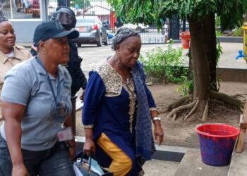 Mary Broh, escorted by security officers, arrives at court following her arrest in the Saudi rice corruption scandal after police breached protocol by raiding former President Ellen Johnson Sirleaf’s residence.