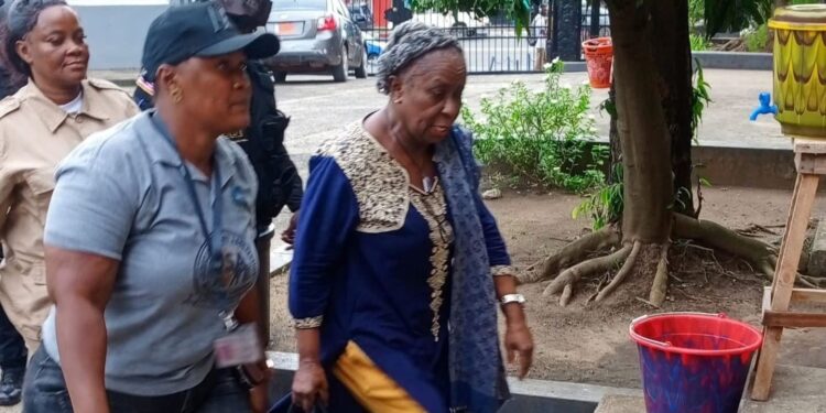 Mary Broh, escorted by security officers, arrives at court following her arrest in the Saudi rice corruption scandal after police breached protocol by raiding former President Ellen Johnson Sirleaf’s residence.