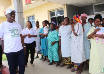 Rev. Dr. Alvin Attah of AMEU addresses a group of mothers and newborns at JFK Maternity Center after the university cleared medical bills as part of its 30th anniversary humanitarian celebration.