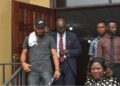 Peach H. Bility, son of Rep. Musa Bility, wearing black face cap exits Criminal Court C in Monrovia after pleading guilty to drug trafficking charges, accompanied by his lawyer and security personnel