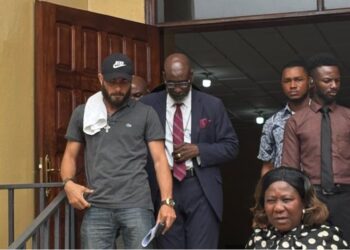 Peach H. Bility, son of Rep. Musa Bility, wearing black face cap exits Criminal Court C in Monrovia after pleading guilty to drug trafficking charges, accompanied by his lawyer and security personnel