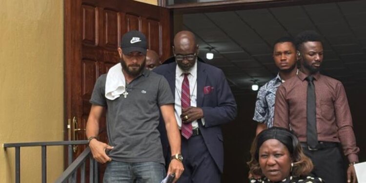 Peach H. Bility, son of Rep. Musa Bility, wearing black face cap exits Criminal Court C in Monrovia after pleading guilty to drug trafficking charges, accompanied by his lawyer and security personnel