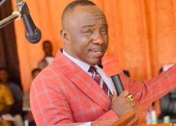 Senator Prince Moye speaking at a public event, wearing a red checkered suit and addressing political tensions in Bong County amid protest allegations.
