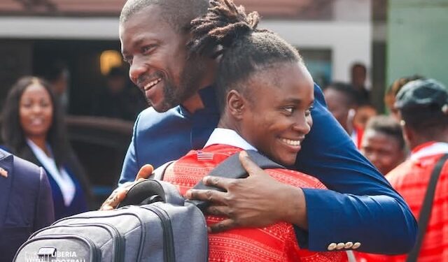 LFA president Mustapha Raji embraces a smiling player from the Liberia Women’s National Football Team as they return from Mauritania after finishing third at the 2025 WAFU Zone A Women’s Cup. Four players, proudly wearing medals, pose with Quamie in a celebratory photo.