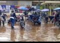 Motorbike riders wash their bikes in floodwater at the entrance of Liberia’s SKD Sports Complex, highlighting the stadium’s deteriorating condition.