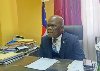 Senator Numene T.H. Bartekwa seated at his office in Monrovia, surrounded by legislative documents, calling for the termination of Atlantic Resources' logging concession