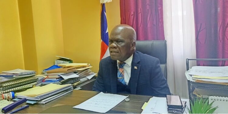 Senator Numene T.H. Bartekwa seated at his office in Monrovia, surrounded by legislative documents, calling for the termination of Atlantic Resources' logging concession