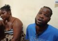 A man and a woman, identified as Zarwu Kennedy, 32, and Princess Varnah, 30, sit indoors after their arrest in Bong County, Liberia, for alleged drug trafficking. The woman appears distressed, resting her head on her hand, while the man looks upward, speaking.