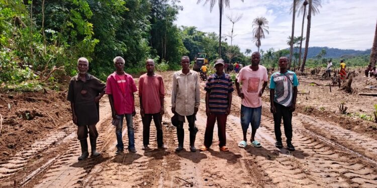 Local leaders and engineers stand on a newly cleared road section in Zota District, Bong County, marking progress on a six-kilometer community-led project.