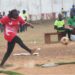 A female kickball player in red uniform kicks the ball during a dusty league match in Liberia, highlighting the sport’s resilience amid neglect