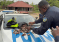 Liberian police officer displays confiscated money on patrol car during CENTAL corruption investigation release in rural Liberia