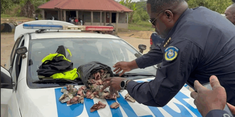 Liberian police officer displays confiscated money on patrol car during CENTAL corruption investigation release in rural Liberia