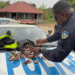 Liberian police officer displays confiscated money on patrol car during CENTAL corruption investigation release in rural Liberia