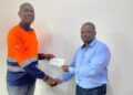 Joseph Sloan of ArcelorMittal Liberia presents a $50,000 check to Assistant Professor Emmanuel A. Donseah of Nimba University to support the school’s mining and geology program.