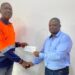 Joseph Sloan of ArcelorMittal Liberia presents a $50,000 check to Assistant Professor Emmanuel A. Donseah of Nimba University to support the school’s mining and geology program.