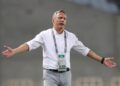Antoine Hey gestures on the touchline during a match, wearing a white shirt and lanyard, as he takes charge of Algerian club ES Sétif.