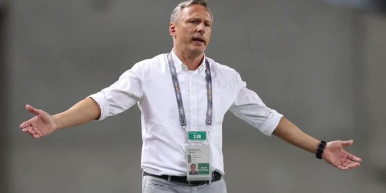 Antoine Hey gestures on the touchline during a match, wearing a white shirt and lanyard, as he takes charge of Algerian club ES Sétif.