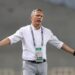 Antoine Hey gestures on the touchline during a match, wearing a white shirt and lanyard, as he takes charge of Algerian club ES Sétif.