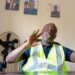 Harper Port Director Augustine Nuefville speaking in office with high-visibility vest and Liberian presidential portraits on the wall