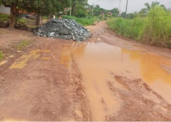 Muddy, pothole-ridden section of the Gbarnga-Kokoyah road in Bong County with scattered crushed rock from MNG Gold trucks