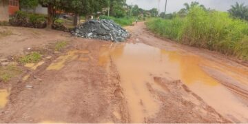 Muddy, pothole-ridden section of the Gbarnga-Kokoyah road in Bong County with scattered crushed rock from MNG Gold trucks