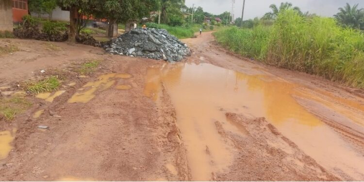 Muddy, pothole-ridden section of the Gbarnga-Kokoyah road in Bong County with scattered crushed rock from MNG Gold trucks