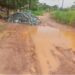 Muddy, pothole-ridden section of the Gbarnga-Kokoyah road in Bong County with scattered crushed rock from MNG Gold trucks