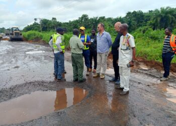 Bea Mountain and Ministry of Public Works officials inspect rehabilitation works on the Bomi–Monrovia highway amid muddy road conditions and construction equipment