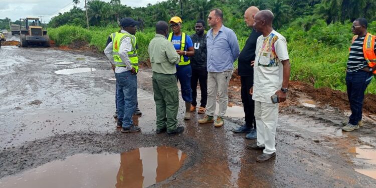 Bea Mountain and Ministry of Public Works officials inspect rehabilitation works on the Bomi–Monrovia highway amid muddy road conditions and construction equipment