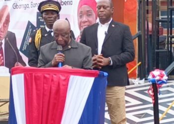 President Joseph Boakai speaks at the launch of Liberia’s first regional passport center in Gbarnga, Bong County, flanked by security personnel and officials under red, white, and blue decorations