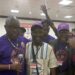 Bong County lawmakers Moye, Cole, and Kollie smile and embrace during reconciliation at the UBCAA diaspora convention in Kentucky