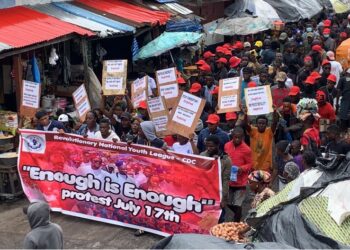 Members of the CDC Youth League hold banners and placards in a crowded street rally endorsing the July 17 “Enough is Enough” protest in Monrovia.