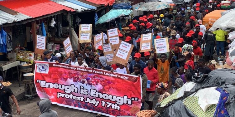 Members of the CDC Youth League hold banners and placards in a crowded street rally endorsing the July 17 “Enough is Enough” protest in Monrovia.