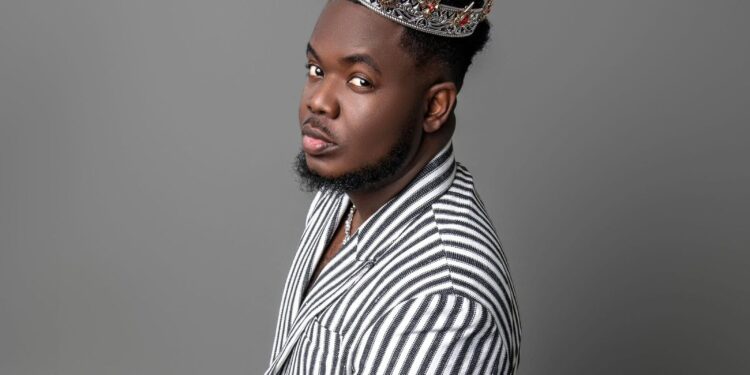 Liberian artist CIC wears a silver crown and a striped suit, embodying his “Local Champion” persona in a powerful promotional portrait for his 2025 album release.