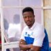 Coach Mohamed Kallon seated on the bench during a Sierra Leone national team match, wearing team gear with initials “MK.”