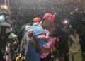 Christoph the Change kisses his wife on stage in front of a massive crowd at SKD Stadium during his historic Independence Day concert, capturing an emotional moment of love, victory, and cultural pride.