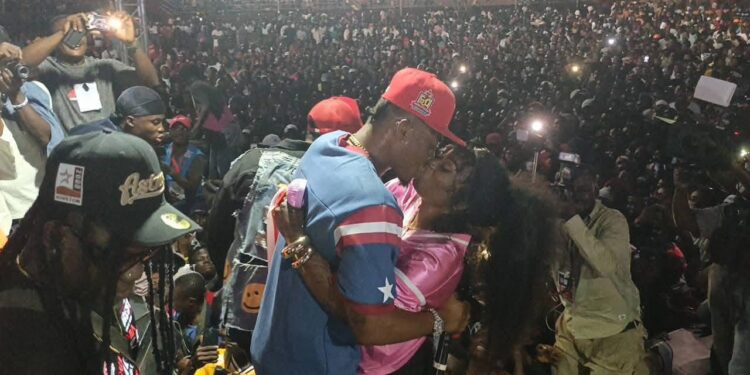 Christoph the Change kisses his wife on stage in front of a massive crowd at SKD Stadium during his historic Independence Day concert, capturing an emotional moment of love, victory, and cultural pride.