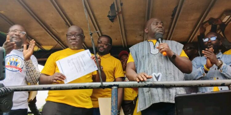 Representative Marvin Cole holds up CMC party document as Musa Bility looks on during a political rally in Bong County.