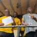 Representative Marvin Cole holds up CMC party document as Musa Bility looks on during a political rally in Bong County.