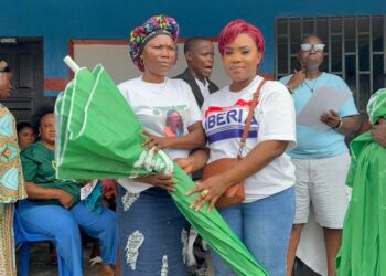 Deputy Minister Cornelia Kruah distributes green umbrellas to female market vendors during a community empowerment ceremony in New Georgia Estate, District 13.