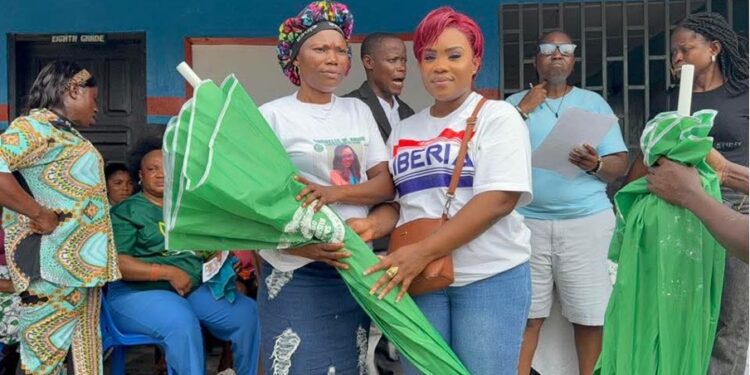 Deputy Minister Cornelia Kruah distributes green umbrellas to female market vendors during a community empowerment ceremony in New Georgia Estate, District 13.