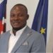 Township Commissioner Edward Horton Lahai stands near national and EU flags, highlighting governance challenges faced by local officials across Liberia.