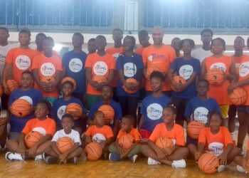 Group photo of young boys and girls in branded Flames Basketball and LBA jerseys during youth training camp at Stella Maris Gym in Monrovia, Liberia.