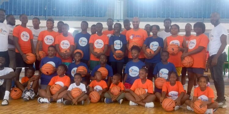Group photo of young boys and girls in branded Flames Basketball and LBA jerseys during youth training camp at Stella Maris Gym in Monrovia, Liberia.