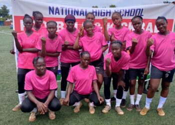 Liberian high school students compete in football during the 2025 National Championship, wearing colorful school uniforms under stadium lights.
