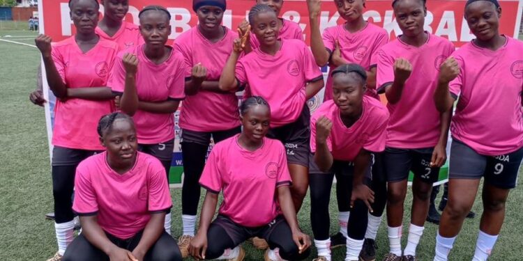 Liberian high school students compete in football during the 2025 National Championship, wearing colorful school uniforms under stadium lights.