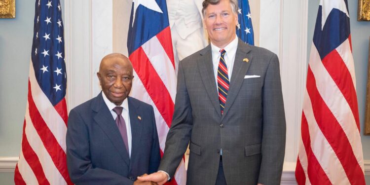 Liberian President Joseph Boakai shakes hands with U.S. Deputy Secretary of State Christopher Landau during a bilateral meeting in Washington, D.C., flanked by Liberian and American flags