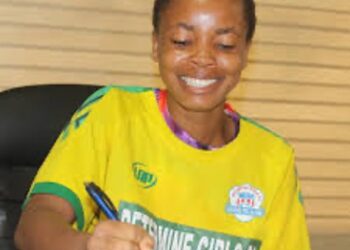 Liberian footballer Jessica Quachie signs contract wearing a yellow Determine Girls jersey