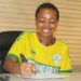 Liberian footballer Jessica Quachie signs contract wearing a yellow Determine Girls jersey