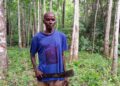 Liberian farmer Joseph Dumoe stands with cutlass in his Suakoko District farmland, wearing a political campaign shirt